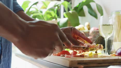 sección media de un hombre afroamericano de pie en la cocina y cocinando la cena