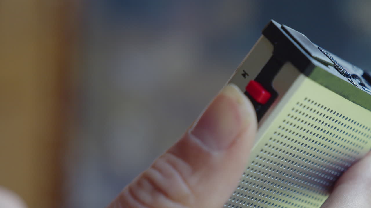 la mano sostiene la grabadora y controla el rebobinado y la grabación de la cinta