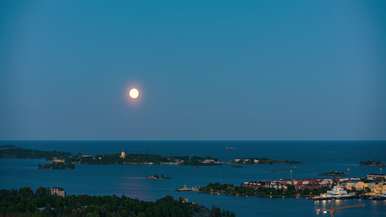 Timelapse da lua nascendo sobre Suomenlinna e Katajanokka, hora azul em Helsinque.