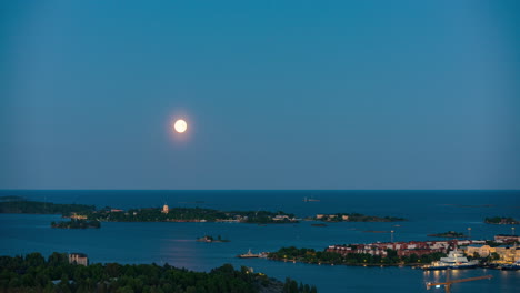 el lapso de tiempo de la luna que se levanta sobre suomenlinna y katajanokka, hora azul en helsinki