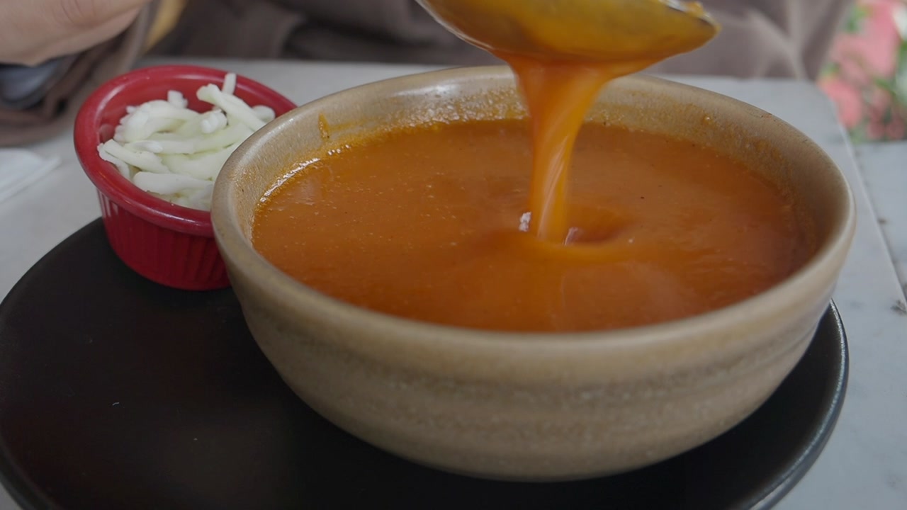 Spoon Stirring Creamy Orange Tomato Soup in a Bowl