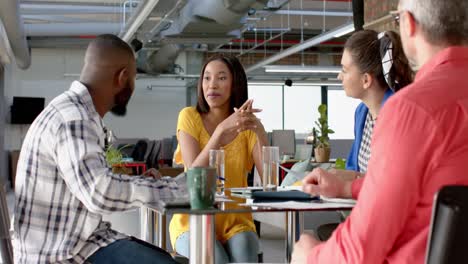 team of diverse colleagues discussing while sitting on a table together at office