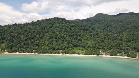 Toma-De-Drones-De-Una-Larga-Playa-De-Arena-Blanca-Con-Selva-Tropical-Detrás-Y-Montañas