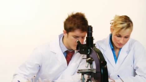 male and female scientist looking through a microscope