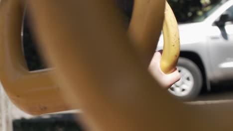 slow motion close-up of a child's hands as she swings on rings in a park and then lets go at the end