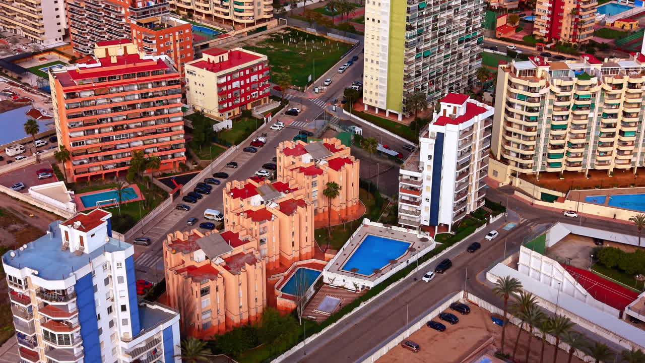Vista aérea de edifícios de apartamentos residenciais com piscinas. Perspectiva de ângulo alto de edifícios modernos de vários andares, telhados vermelhos, palmeiras e piscinas ao ar livre em um resort turístico.