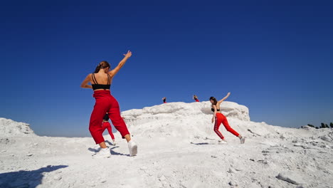 women dancing in red pants on white landscape