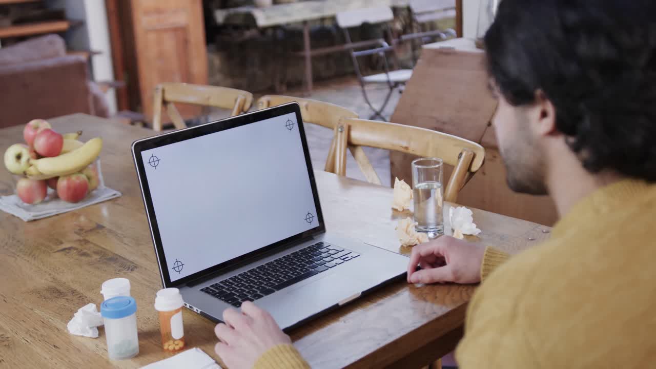 Uomo caucasico con farmaci che effettua una videochiamata usando un laptop, spazio per il testo sullo schermo, al rallentatore