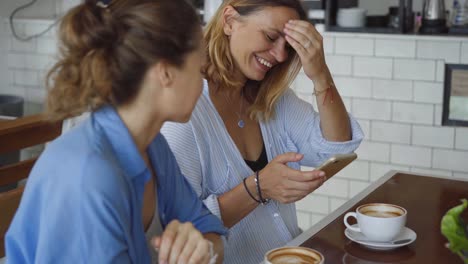 two women enjoying coffee and mobile phones in a cafe