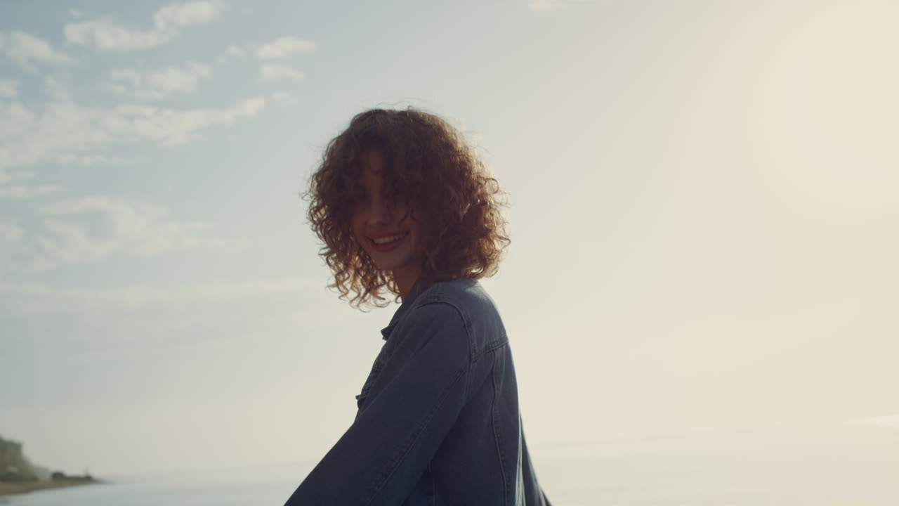 chica juguetona posando para la cámara en la orilla del mar. mujer sonriente dando la vuelta en la playa