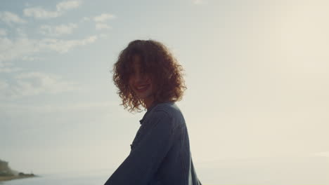 Playful-girl-posing-on-camera-at-seashore.-Smiling-woman-turning-around-on-beach