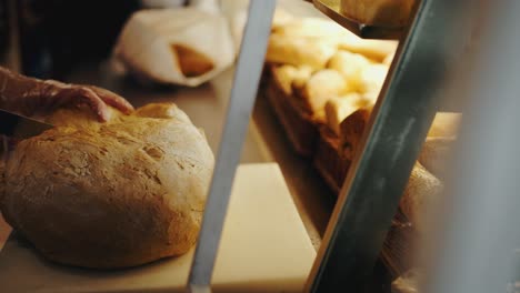 slow motion tracking shot of the hand of a person cutting a big bread