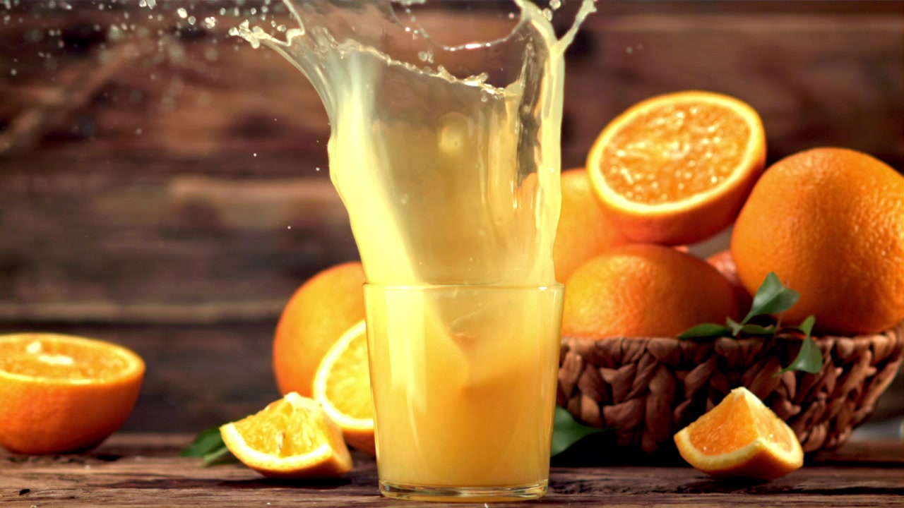 Orangenscheibe fällt mit Spritzer in frischen Orangensaft.