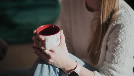 mujer sosteniendo una taza de café en una casa brillante durante navidad