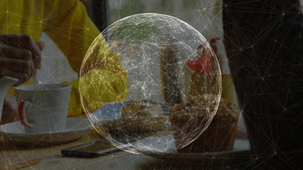 Digital network globe hovering above tabletop with hands stirring coffee near smartphone and pastry