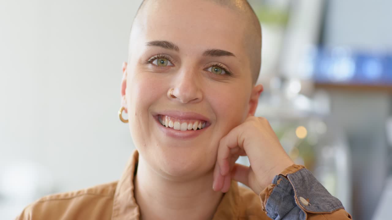 Woman resting chin on hand at kitchen countertop, hearing offscreen remark, smiling then laughing