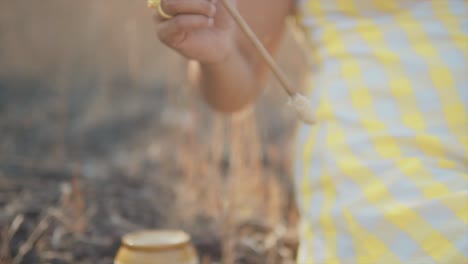 dreamy slow motion close up shot of a young beautiful indian woman dipping a brush into a pot and painting a broken clay pot in her hands outdoors