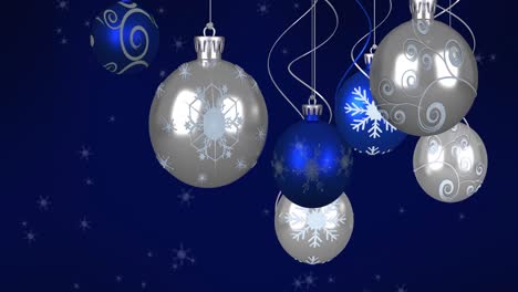 Animation-of-baubles-and-snow-falling-on-dark-blue-background