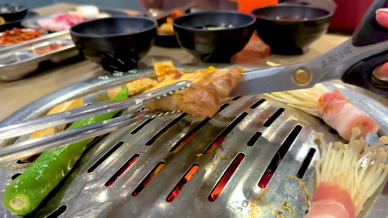 Grilled meat and vegetables on a Korean BBQ grill in a Bangkok restaurant. Vibrant, dynamic cooking scene with close-up shots