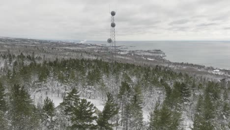 self-support cell tower within the snowy forest in winter. - aerial shot