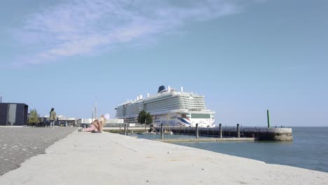 little girl sitting ground, huge cruise ship in background, lisbon, portugal