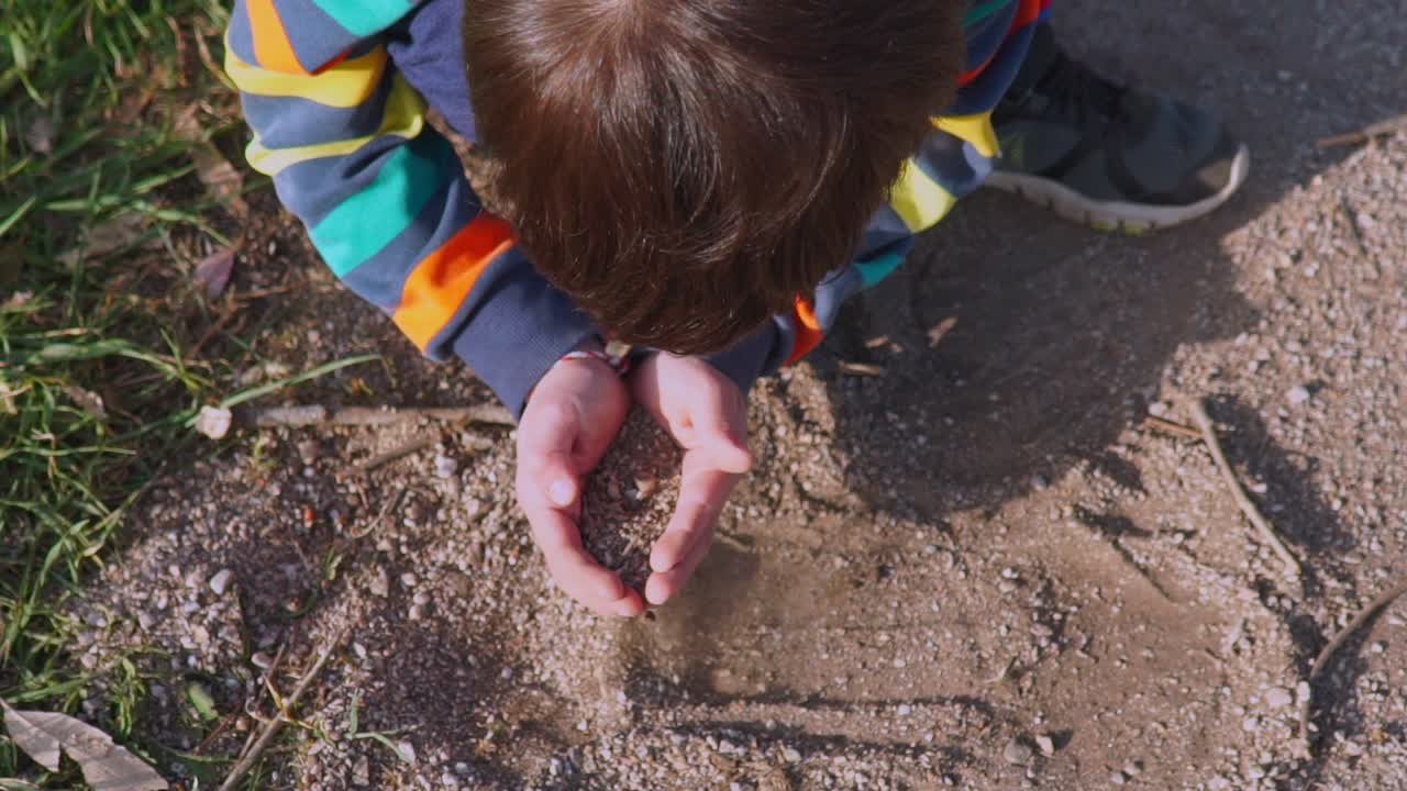 cabeza superior, vista de pájaro de un niño caucásico, jugando con el suelo al aire libre