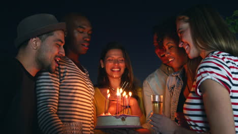 friends celebrating with a birthday cake outdoors at night