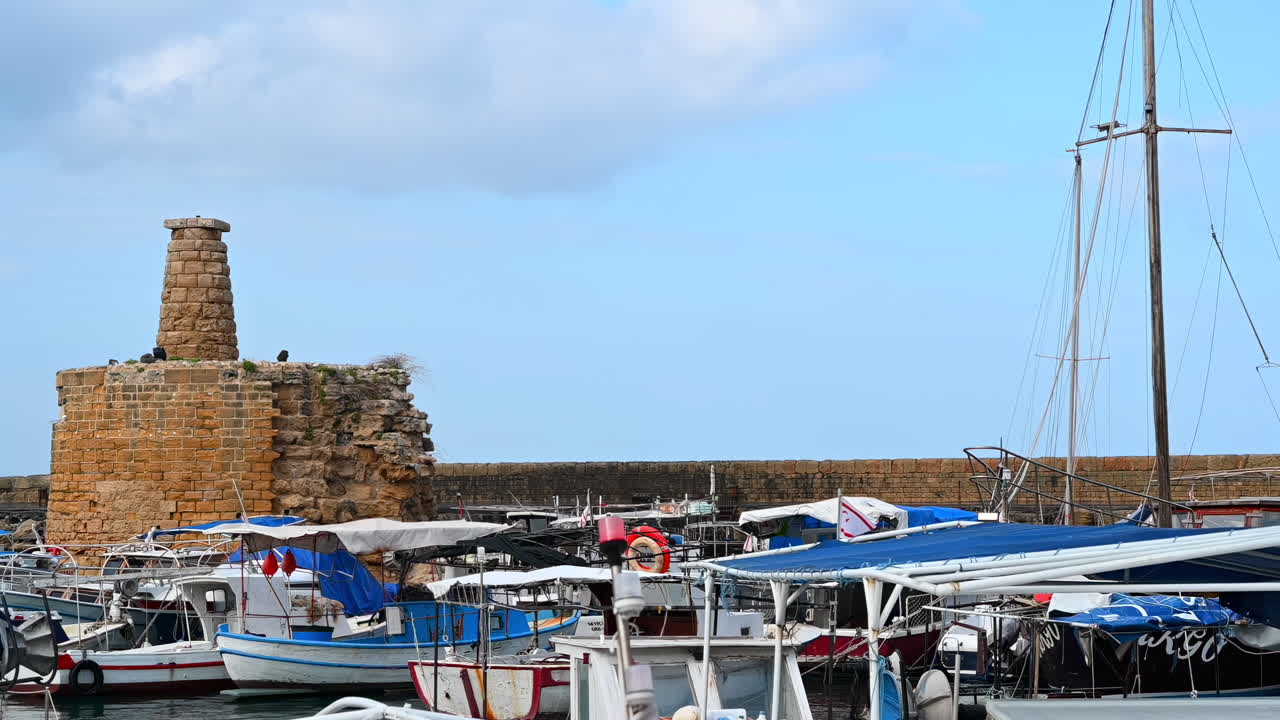 Kyrenia, Cyprus - February 12, 2019: Boats docked in the Kyrenia Harbour with the Chain Tower on the background