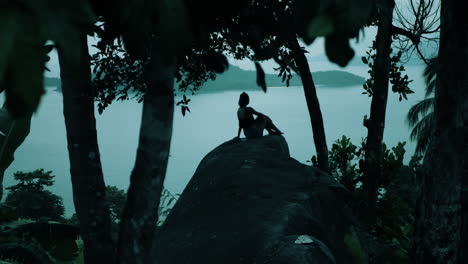 woman sitting on a rock with ocean view