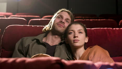 pareja sentada en el cine sonriendo y mirando a la cámara