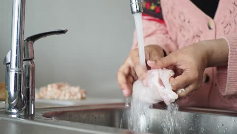 lavado de carne cruda bajo agua corriente