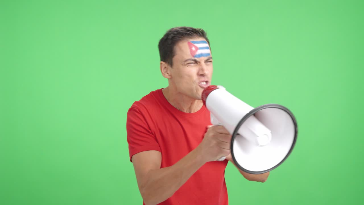 Excited man with cuban flag on face using a megaphone