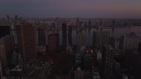 Aerial-view-of-tall-apartment-buildings-along-river-after-sunset.-Heavy-traffic-in-streets.-Manhattan,-New-York-City,-USA