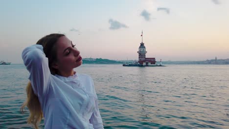 cámara lenta: hermosa chica disfruta de la vista del atardecer del bósforo con vista de la torre de la doncella al fondo en estambul