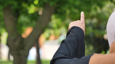 woman in hijab pointing upwards outdoors