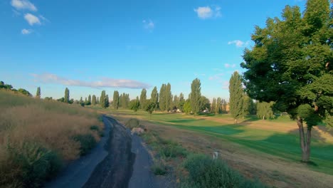 Pan-of-a-green-landscape-with-asphalt-path-for-walking-or-biking-in-the-late-afternoon