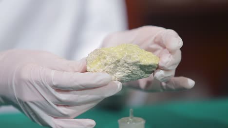 scientist examining a yellow mineral sample