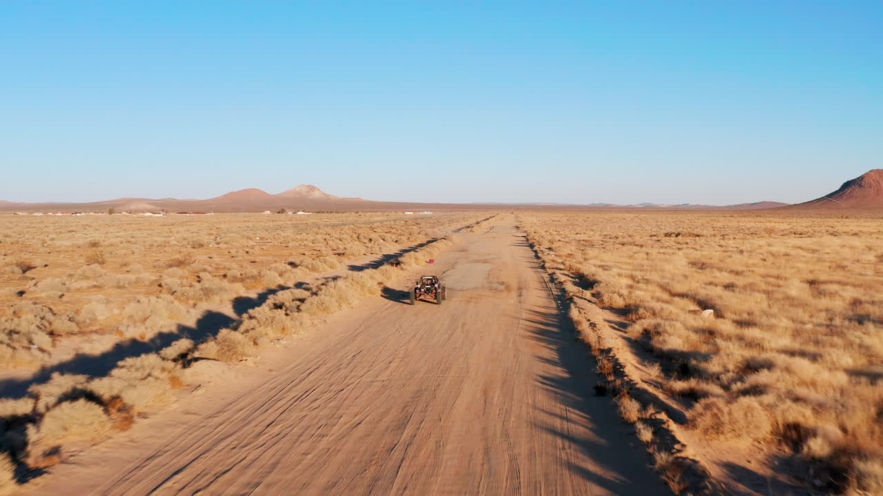 un vehículo todoterreno o un buggy conduciendo por un camino de tierra en el desierto de mojave - vista aérea