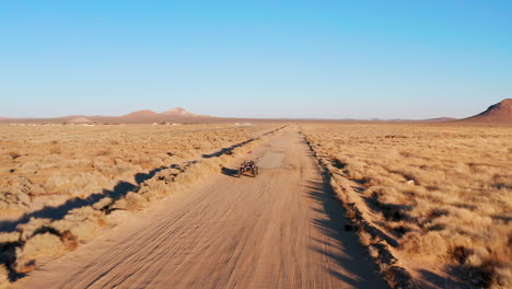 An-off-highway-vehicle-or-dune-buggy-driving-along-a-dirt-road-in-the-Mojave-Desert---Aerial-view