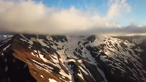 Aerial-view-of-austrian-mountains-snowy-summit-touching-the-clouds