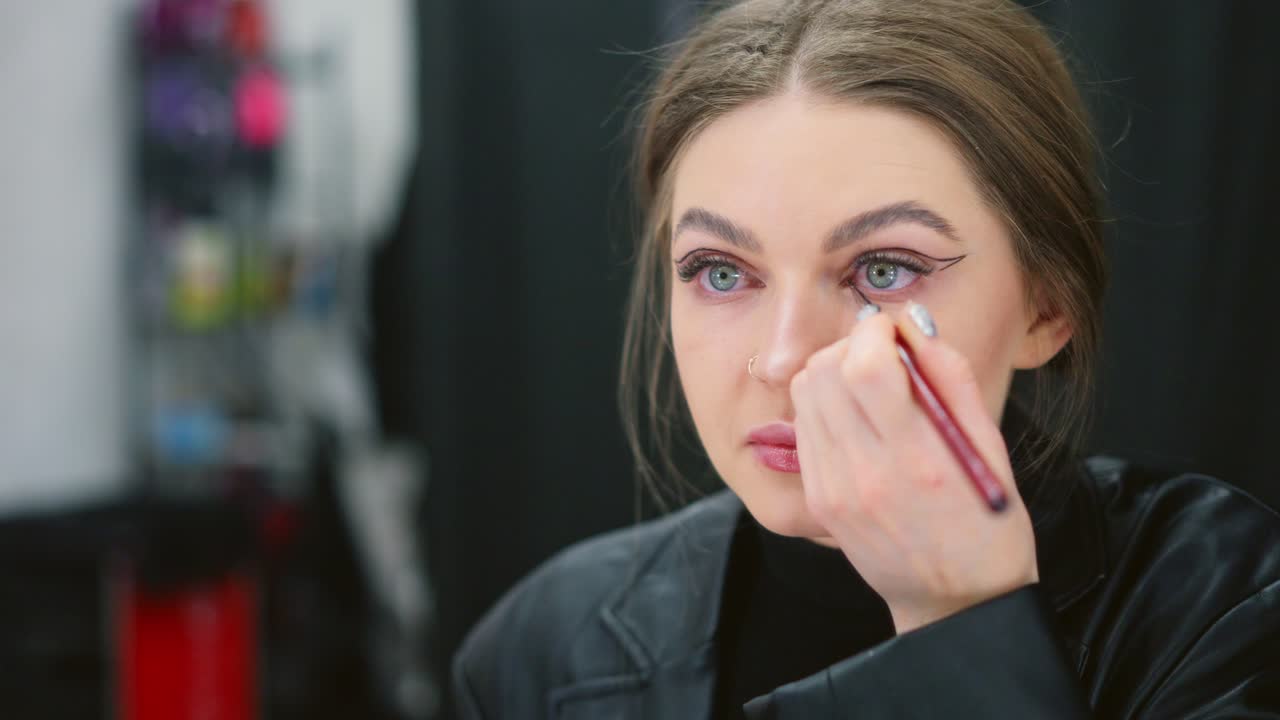 Woman Applying Eyeliner in Mirror