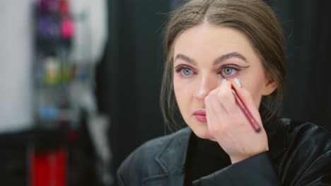 woman applying eyeliner in mirror