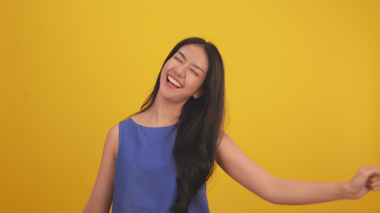 행복한 매력적인 아시아 젊은 여성은 노란색 배경에서 고립되어 춤을 추고, 쾌활한 예쁜 소녀는 태블릿 노트북과 함께 행복합니다, 온라인 음악, 미소 짓고 몸을 움직이면서 긍정적으로 음악을 따르십시오.