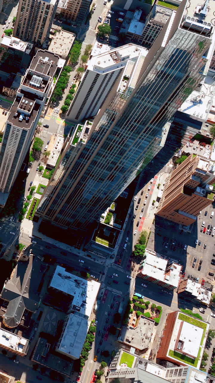Vista aérea de uma rua no centro de Chicago. Um arranha-céu de vidro alto entre edifícios baixos. Vídeo vertical