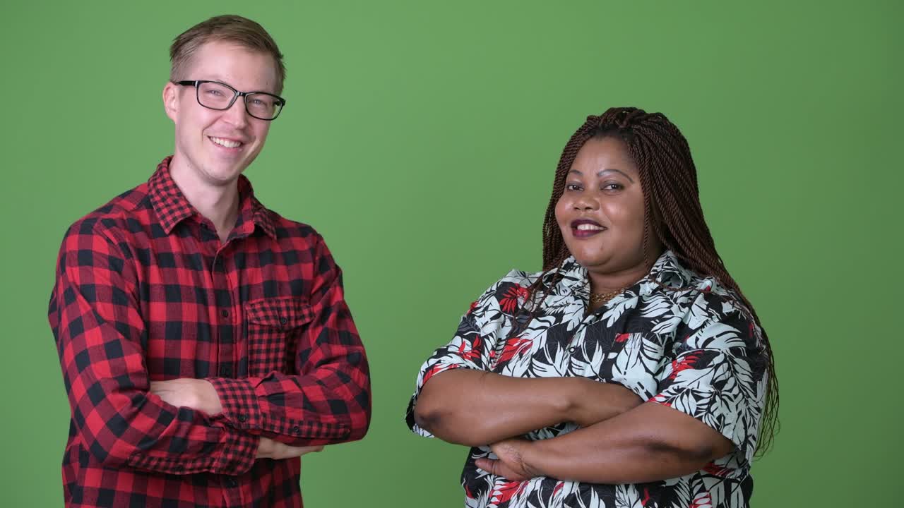 mujer africana con sobrepeso y un joven escandinavo juntos contra un fondo verde