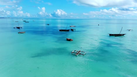 aerial view of a fisherman sails on a wooden boat on clear blue water along a tropical exotic beach in africa