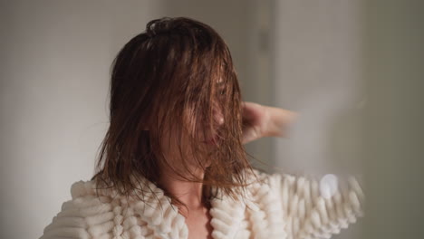 lady poses in front of mirror drying hair in shower. young female moves head with wet hair with positive emotions in spacious place slow motion