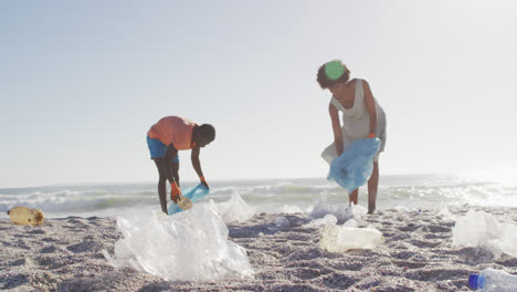 Pareja-Afroamericana-Segregando-Residuos-Juntos-En-Una-Playa-Sucia-Y-Soleada