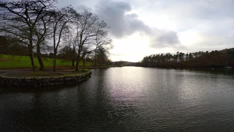 lake windermere in the english lake district, with its iconic wooden jetty, historic stone-built buildings, and moody grey skies