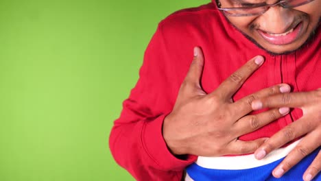 joven sufriendo dolor en el corazón contra la pantalla verde